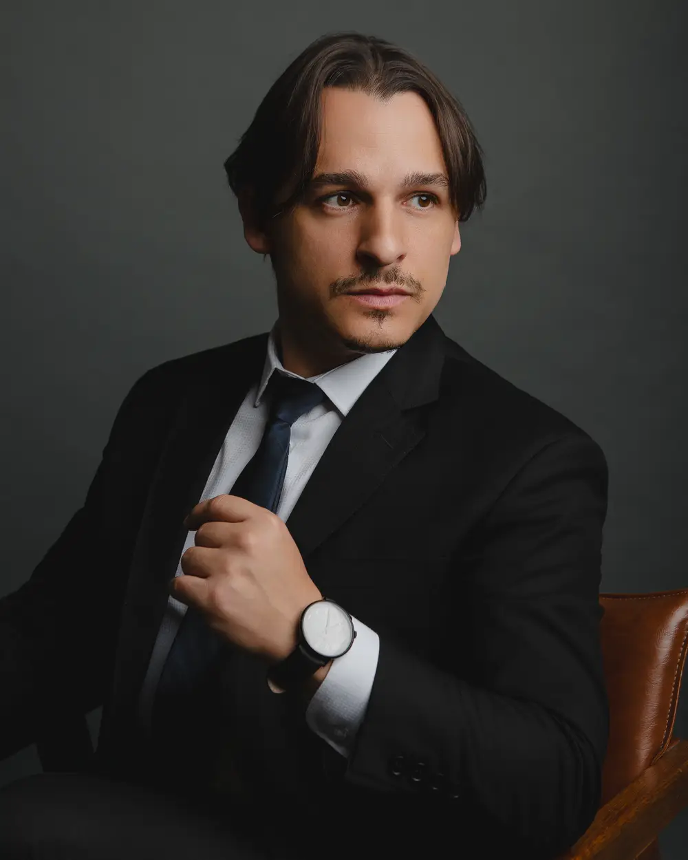 Rafael Dantas in a suit, seated, looking at the camera